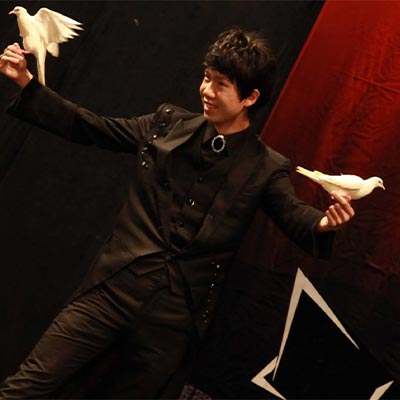 幻影鴿王雙手各持一隻鴿子進行舞台魔術表演