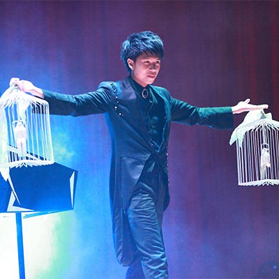幻影鴿王手持兩座鴿籠進行鴿子魔術表演